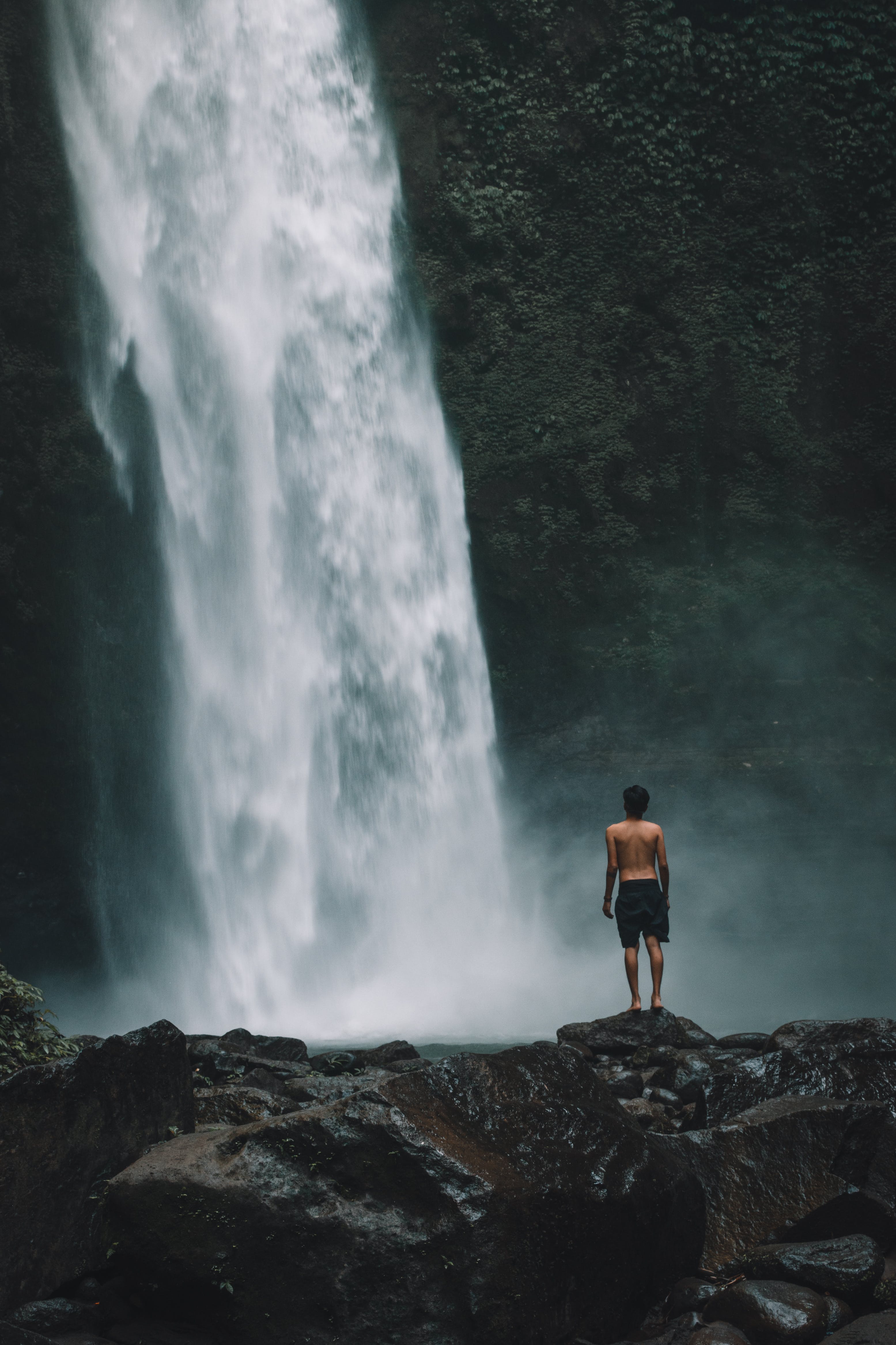 Man Standing On A Rock Near Waterfalls